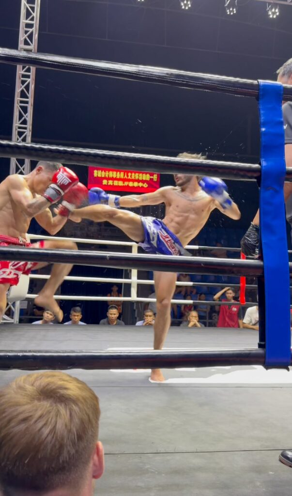 Combat de boxe thaï sur un ring avec un coup de pied porté à l’adversaire pendant un match.