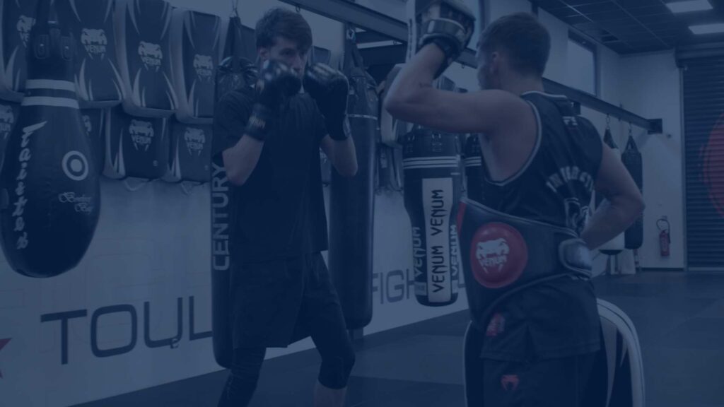 Cours de boxe en duo avec entraînement aux techniques de frappe dans une salle équipée à Toulouse.